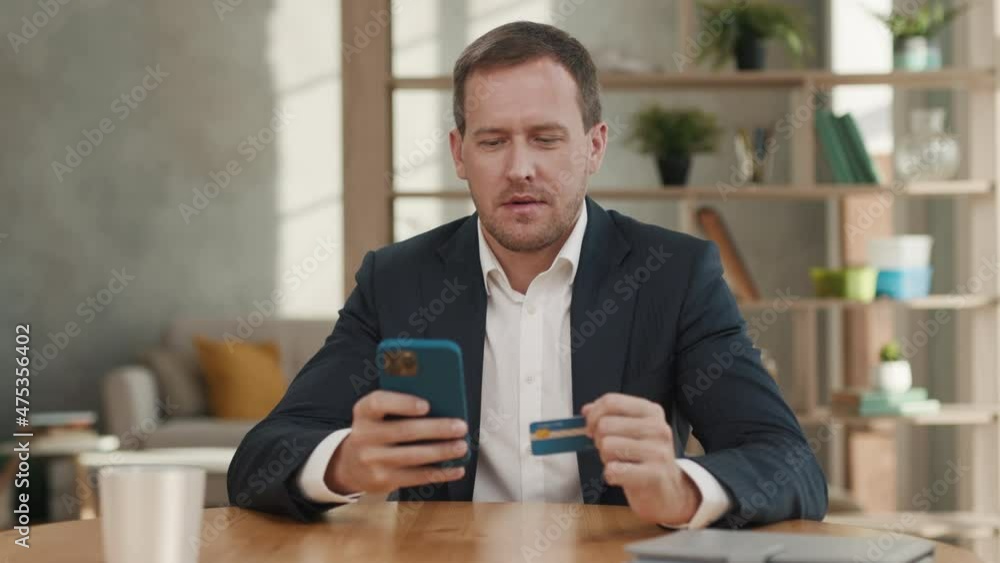 Handsome Man Using Credit Card for Online Shopping on Smartphone Close up. Happy Caucasian Businessperson Holding Cell Phone and Use Internet Bank Payment. Concept Online Purchase Sitting in Home 4k Handsome Man Using Credit Card for Online Shopping on Smartphone Close up. Happy Caucasian Businessperson Holding Cell Phone and Use Internet Bank Payment. Concept Online Purchase Sitting in Home 4k