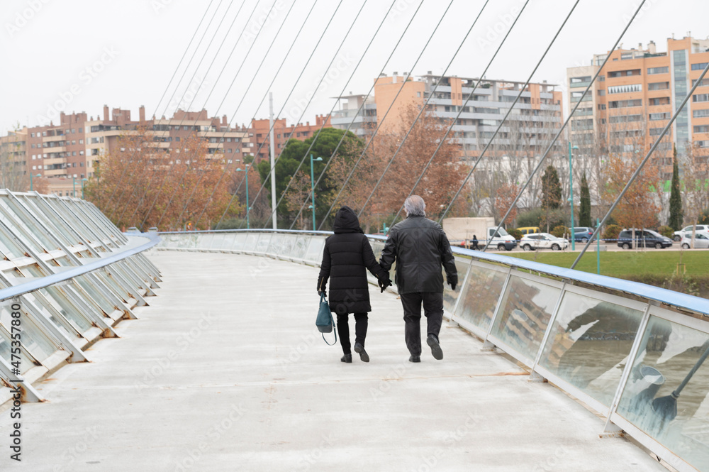 Obraz premium couple walking along the volunteer footbridge over the ebro river in zaragoza spain.