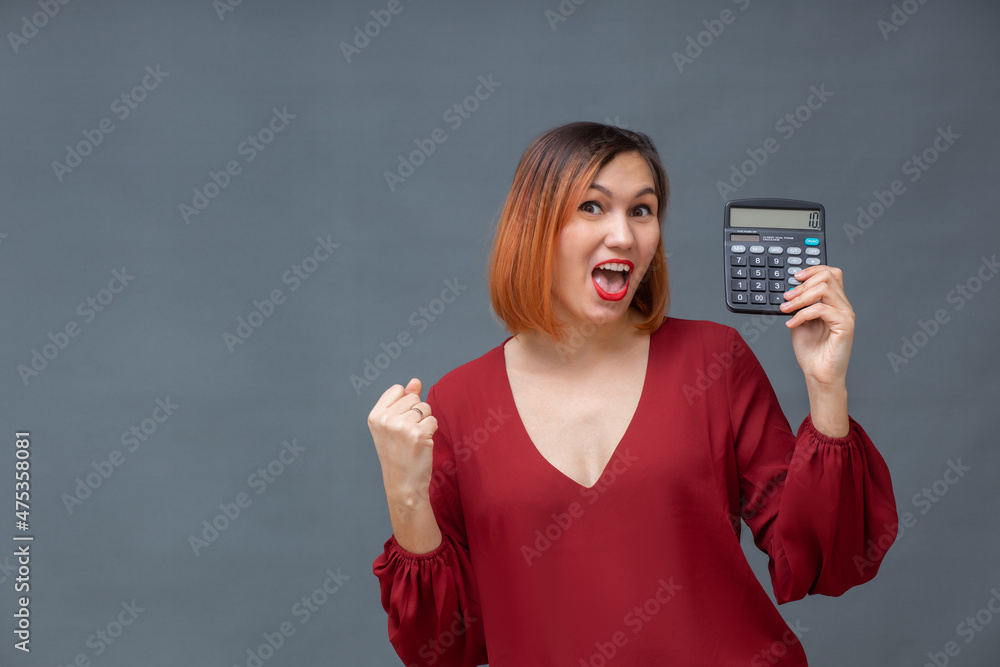 Portrait of a happy female accountant holding a calculator on a gray background. Portrait of a happy female accountant holding a calculator on a gray background.