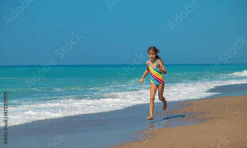 The child runs along the beach near the sea. Selective focus.