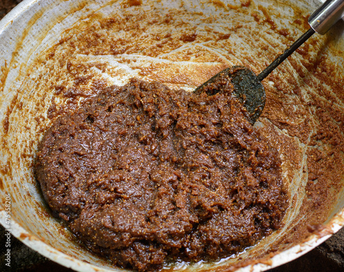 making dodol in a large container, also called kalu dodol in sri lanka, dark sweet candy, made from coconut milk, jaggery and rice flour, sticky, thick, sweet toffee, closeup photo