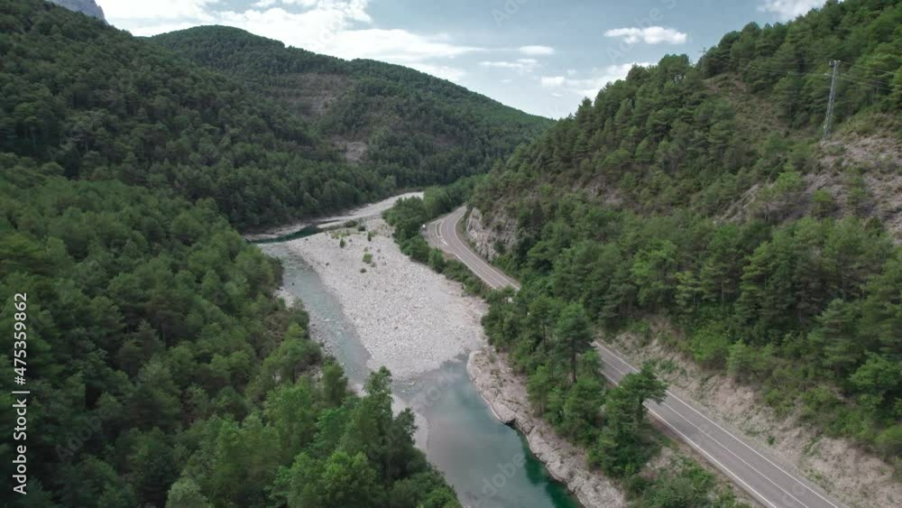 Mountain river with a rocky bank, top view. Green trees and a narrow path meander alongside. Mountain river with a rocky bank, top view. Green trees and a narrow path meander alongside.