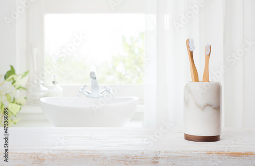 Bamboo toothbrushes in marble glass on blurred bathroom window background