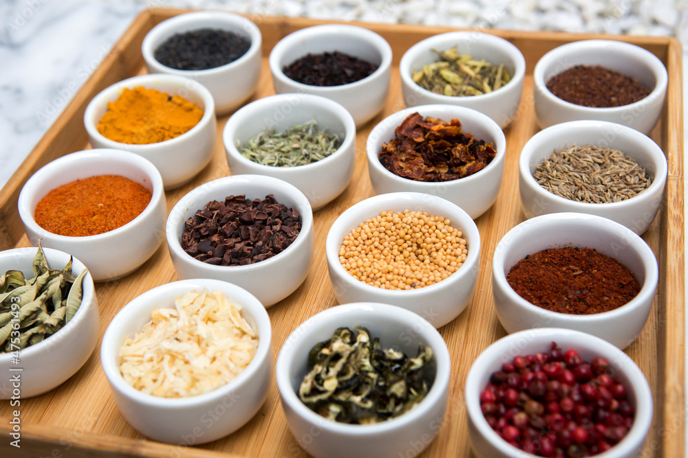 Variety of herbs and spices in containers displayed on tray