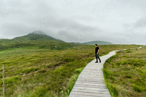 Man on wooden path in mountainous landscape photo