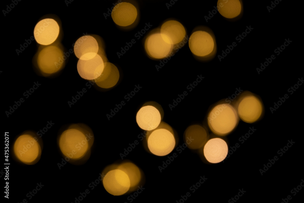 Fototapeta premium Bokeh golden lights background. Blurred lights Christmas garland on a black background.