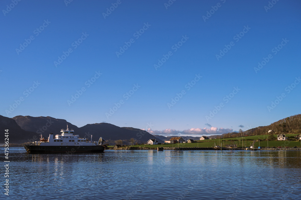 Beautiful landscape of Lusefjord. Mountains and small village. A floating ship.
