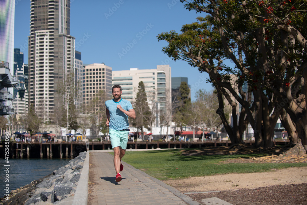 Athletic young runner. Urban sports. Man jogging and running for fitness in the city on a beautiful summer day.