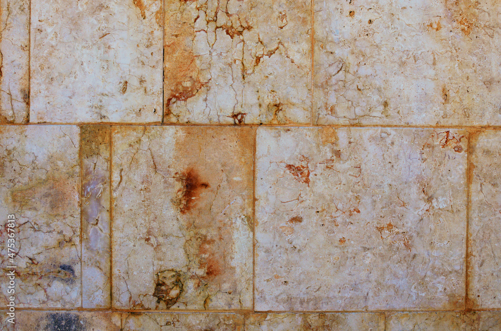 Detailed view of yellow ancient wall. Old wall of large light blocks of marble tiles. Wall with interesting structure. Outdoor and indoor interiors. Grunge texture background Detailed view of yellow ancient wall. Old wall of large light blocks of marble tiles. Wall with interesting structure. Outdoor and indoor interiors. Grunge texture background
