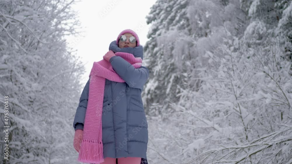 traveler woman in pink clothes, a scarf and a hat and sunglasses is stand in a snowy forest on Christmas in winter traveler woman in pink clothes, a scarf and a hat and sunglasses is stand in a snowy forest on Christmas in winter