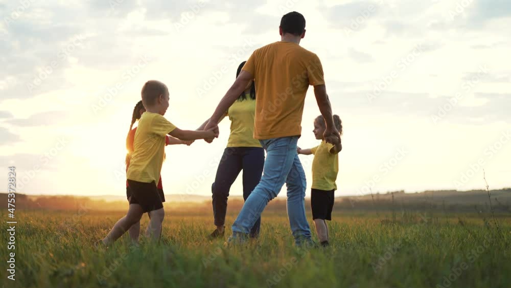 Happy family concept. Group of people hold hands in round dance. Children and parents are play in park on grass. Active lifestyle concept Family on green grass. Happy children play round dance in park Happy family concept. Group of people hold hands in round dance. Children and parents are play in park on grass. Active lifestyle concept Family on green grass. Happy children play round dance in park