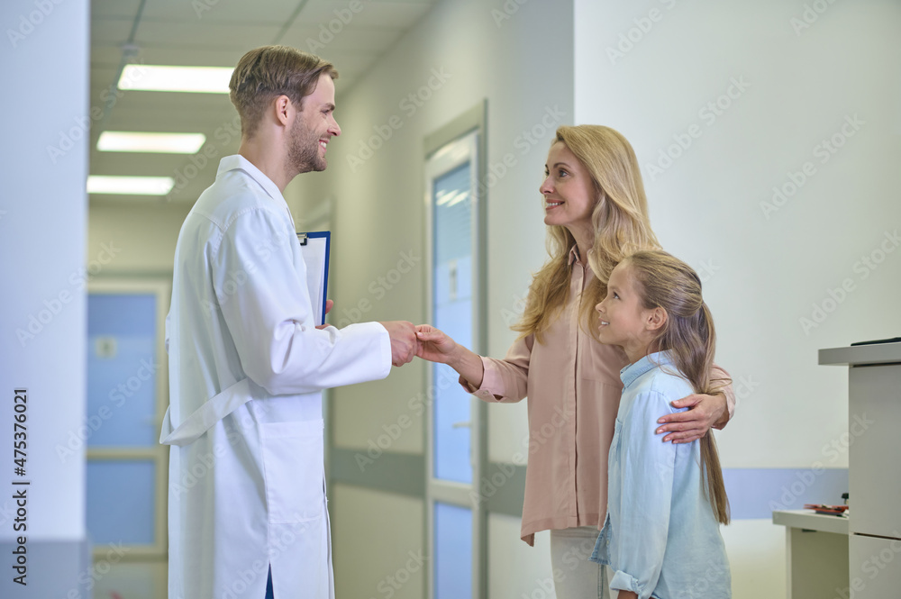 Obraz premium Man shaking hands with woman hugging daughter