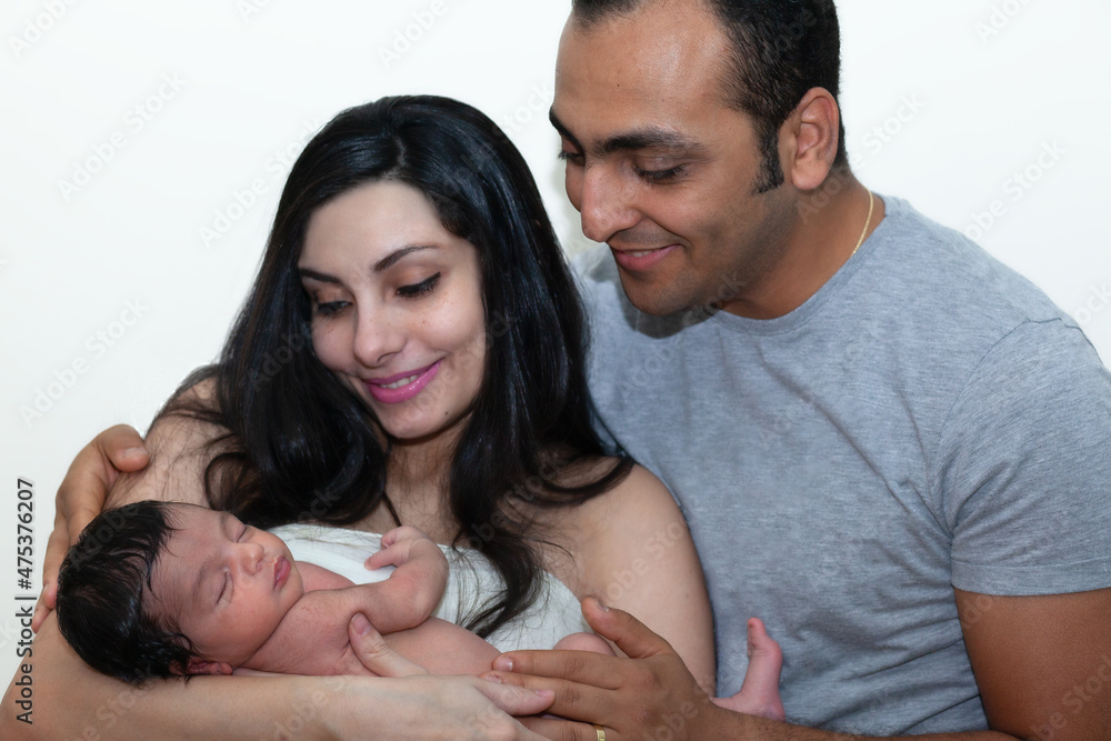 Young parents holding their newborn baby boy and looking at him with love. Young parents holding their newborn baby boy and looking at him with love.