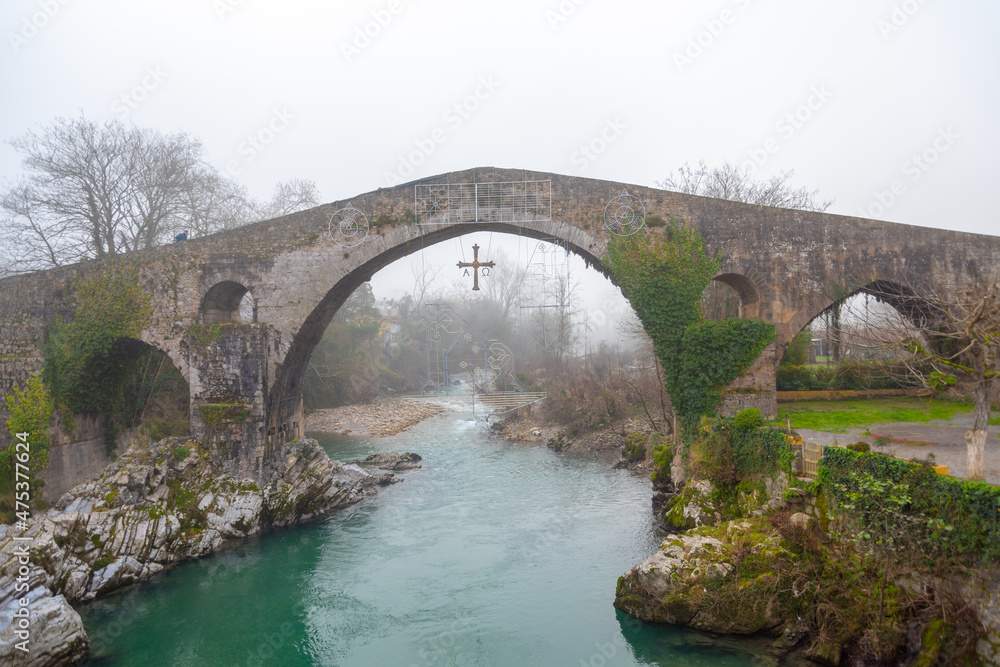 Roman bridge over the river in Cangas de Onis, Asturias. cloudy sky with fog