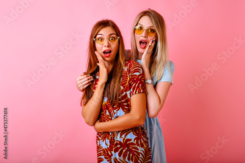 Studio portrait of two positive best friend women having fun at pink background