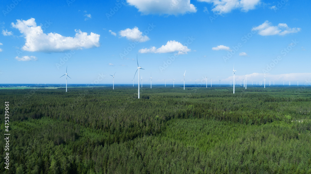Fototapeta premium Aerial view of windmills in green summer forest in Europe. Wind turbines for electric power with clean and Renewable Energy...