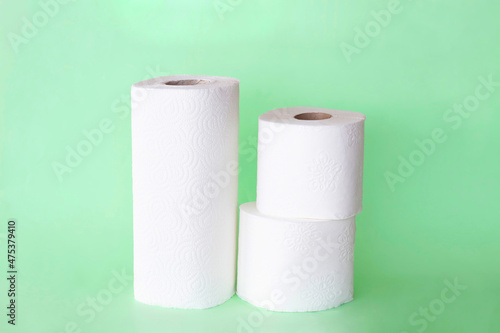 rolls of napkins and toilet paper on green background