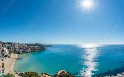 High views of a beach in the Mediterranean Sea with blue sky and sun reflected in the sea