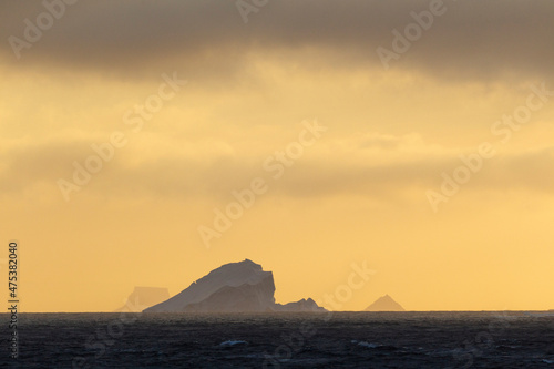Southern Ocean, near South Georgia. An orange sunset gives an eerie feel to the icebergs just offshore. © Danita Delimont
