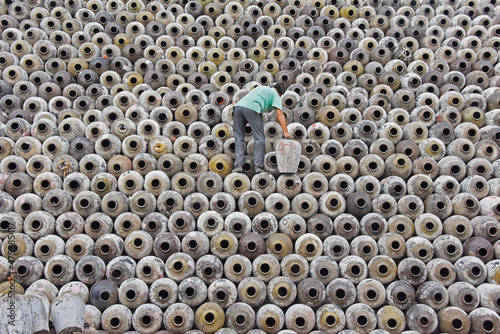 Man stacking wine jars onto the big pile in a winery, Zhejiang Province, China photo