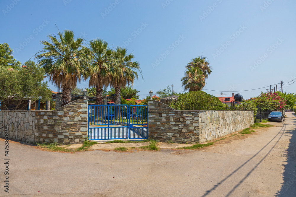 Beautiful view of the interior of a  house with a garden, an entrance gate and a parking lot. Greece. 