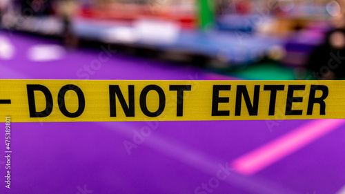 Wide yellow ribbon with writing "DON NOT ENTER" on it against purple background