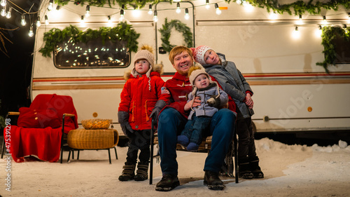 Caucasian man and three sons celebrate Christmas in a mobile home.