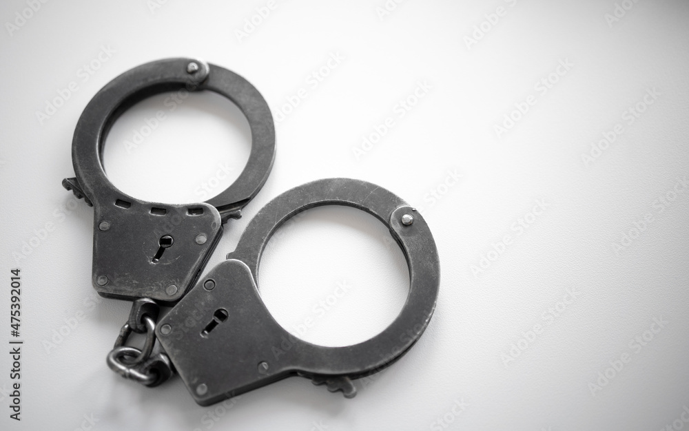 Metal handcuffs of a policeman on a white isolate. A clean place for text. Arrest of the suspect. criminal news. Metal handcuffs of a policeman on a white isolate. A clean place for text. Arrest of the suspect. criminal news.
