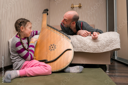 Nervous dad scolds his daughter. The girl plays the bandura loudly, but the man really doesn't like it.