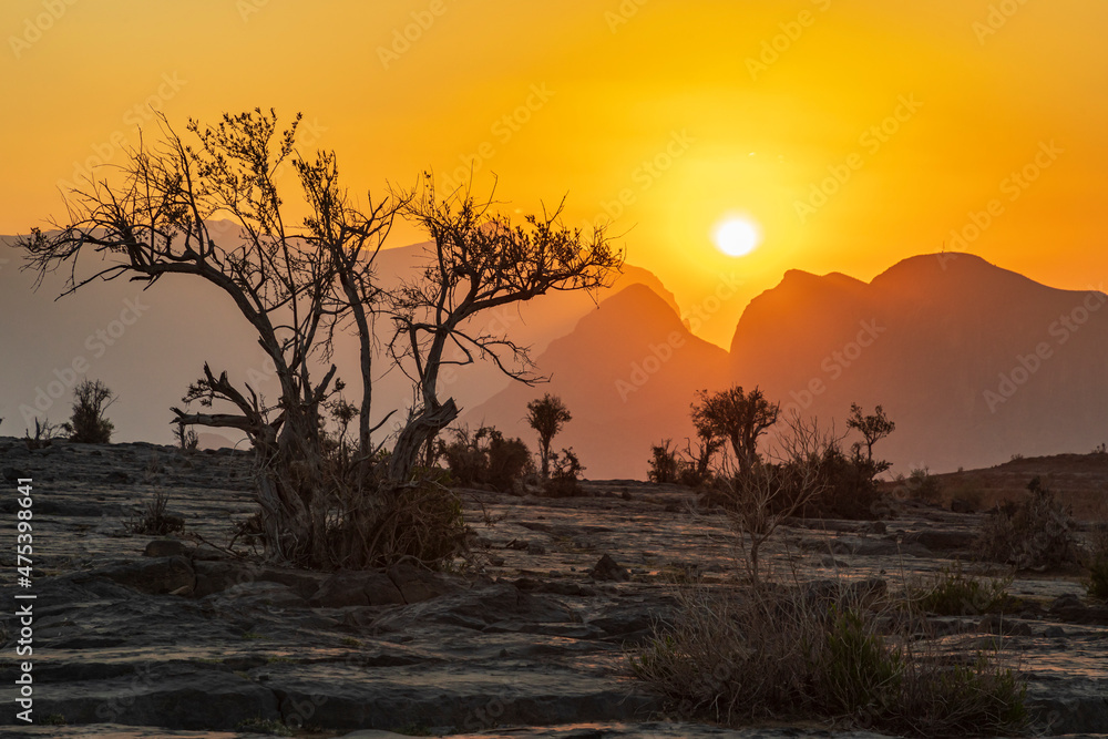 Middle East, Arabian Peninsula, Oman, Ad Dakhiliyah, Al Hamra. The sun setting over mountains in the desert of Oman.