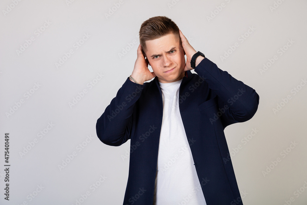 A young man covering his ears with his hands, he does not want to listen to news, gossip, information. Bearing terrible pain. Young guy covered his ears with his hands so as not to hear rumors A young man covering his ears with his hands, he does not want to listen to news, gossip, information. Bearing terrible pain. Young guy covered his ears with his hands so as not to hear rumors