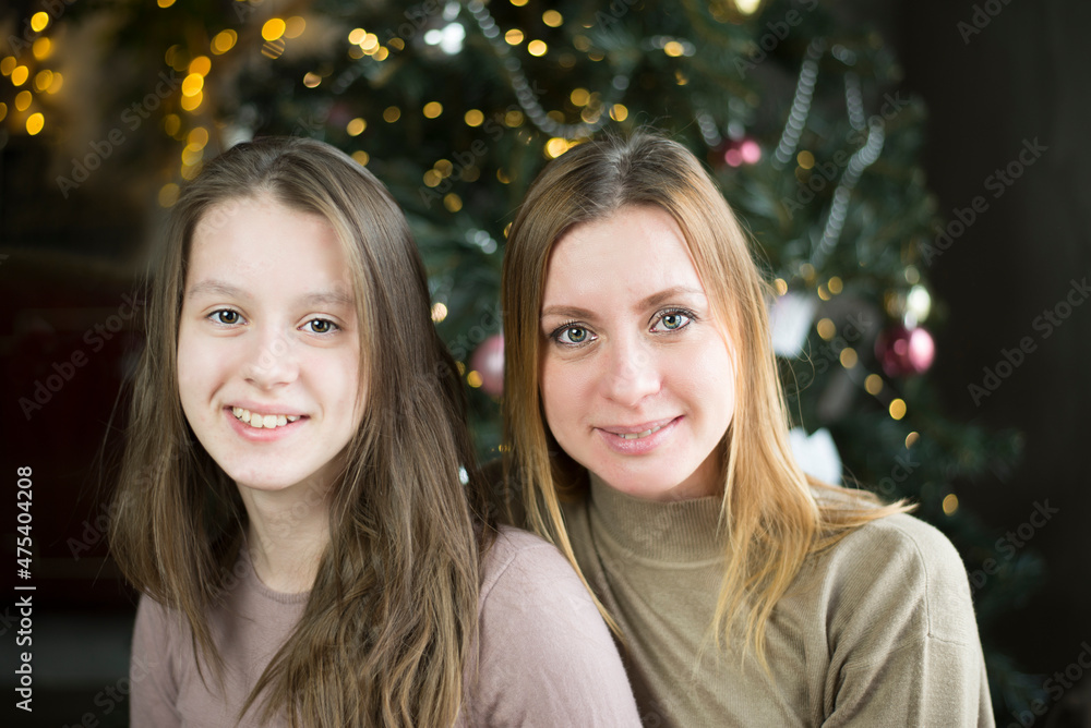 Mother and daughter on the background of a Christmas tree Mother and daughter on the background of a Christmas tree