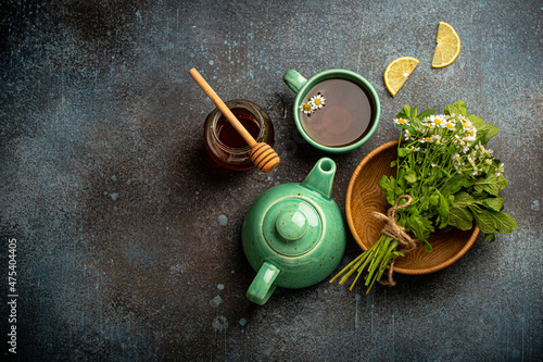Obraz na plátně Herbal tea with camomile, fresh medical herbs and flowers, tea cup, tea pot, jar