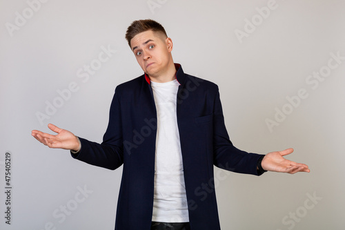 Male young man with a lost expression shrugs his shoulders. The guy spreads his hands and does not know what to say in response photo