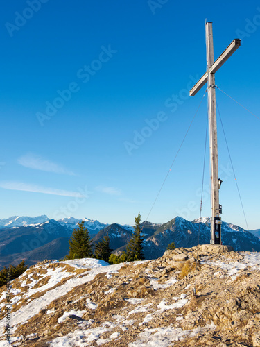 Summit cross of Mt. Jochberg near lake Walchensee, in the background Wetterstein mountain range and Mt. Zugspitze. Germany, Bavaria