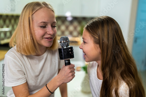 two teenage girls singing a microphone at home