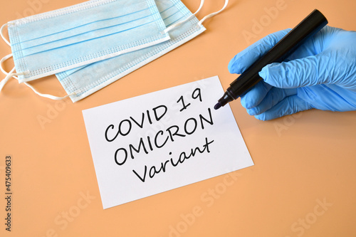 Covid-19 new Omicron variant. Hand in blue glove with marker and writing 