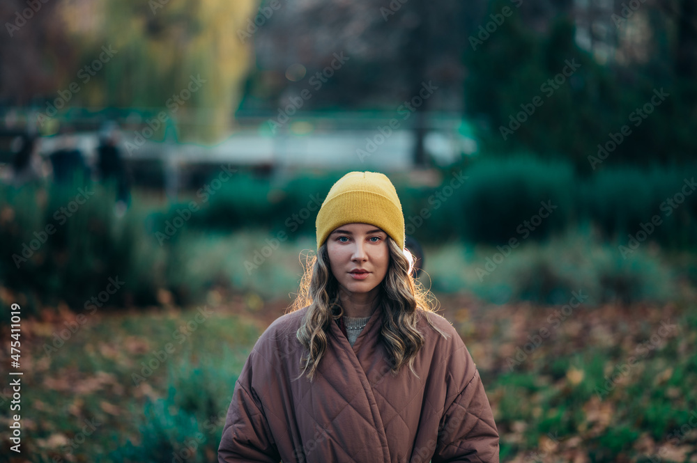 Beautiful young stylish woman wearing coat and a cap in the park Beautiful young stylish woman wearing coat and a cap in the park