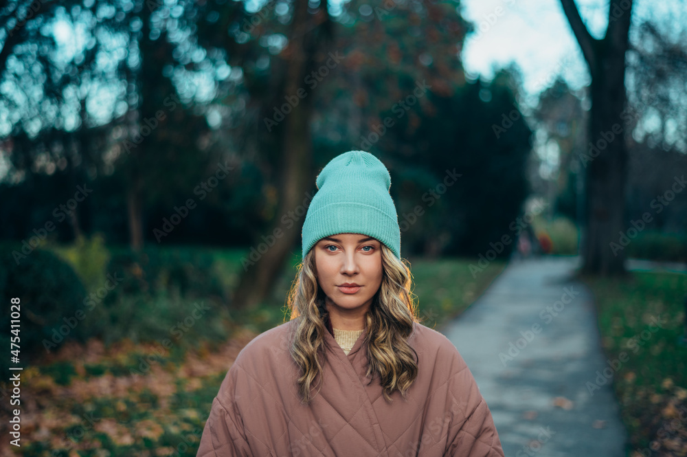 Beautiful young stylish woman wearing coat and a cap in the park Beautiful young stylish woman wearing coat and a cap in the park
