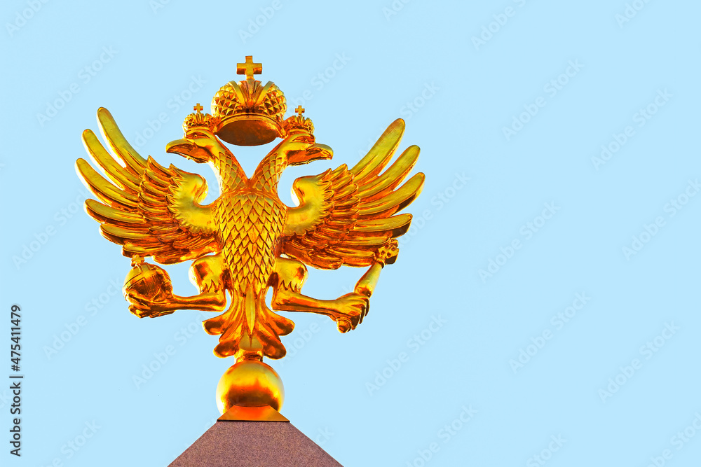 Golden russian double-headed eagle on a blue sky background at sunny day, front view