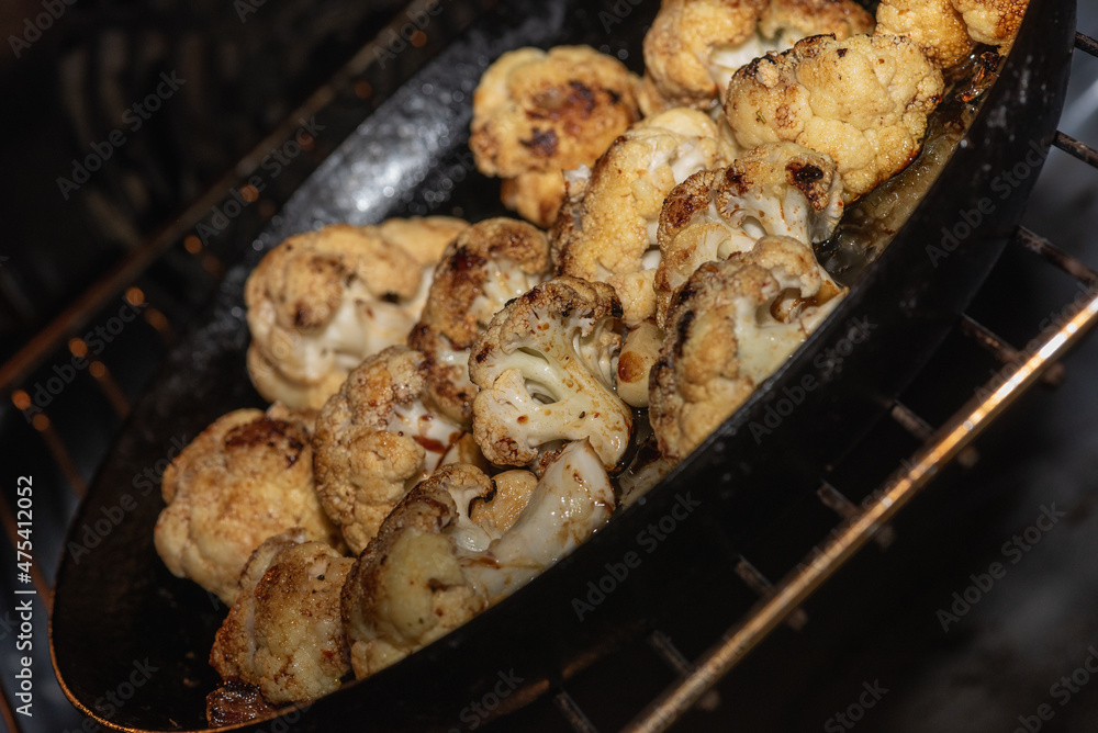 Cooking, fried cauliflower with herbs and spices. Vegetarian food, healthy food baked in the oven. Selective focus. Low key. Sloping, shifted horizon Cooking, fried cauliflower with herbs and spices. Vegetarian food, healthy food baked in the oven. Selective focus. Low key. Sloping, shifted horizon