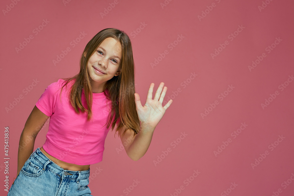 Friendly child girl blogger waving hand in greeting gesture, smiling welcoming subscribes on pink studio background Friendly child girl blogger waving hand in greeting gesture, smiling welcoming subscribes on pink studio background