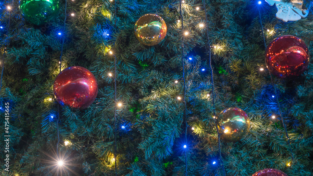 Close-up view of decorated Christmas tree. Beautiful Christmas tree decorated with shiny baubles and lights garland.