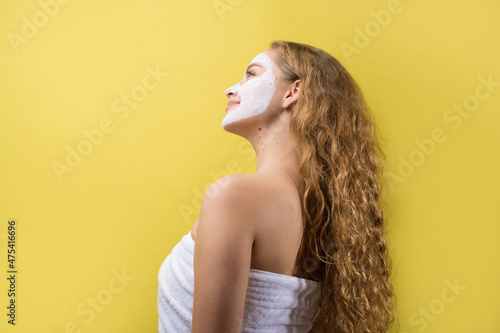 Girl with a cosmetic mask on her face in a white towel.