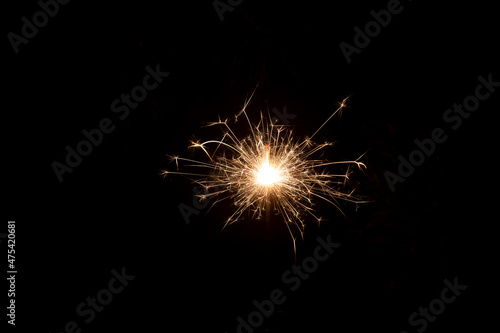 Burning sparkler with sparkles on a long shutter speed. Dark green background
