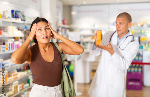 Pharmacist offering headache medicine to patient at pharmacy