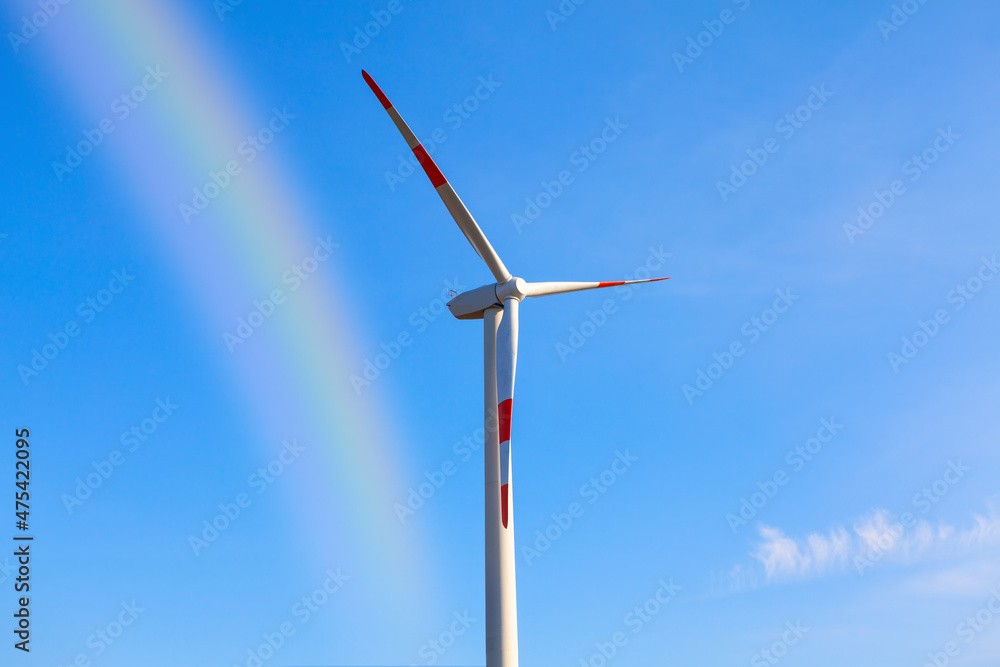 Windmill with rainbow . Wind generator against blue sky Windmill with rainbow . Wind generator against blue sky