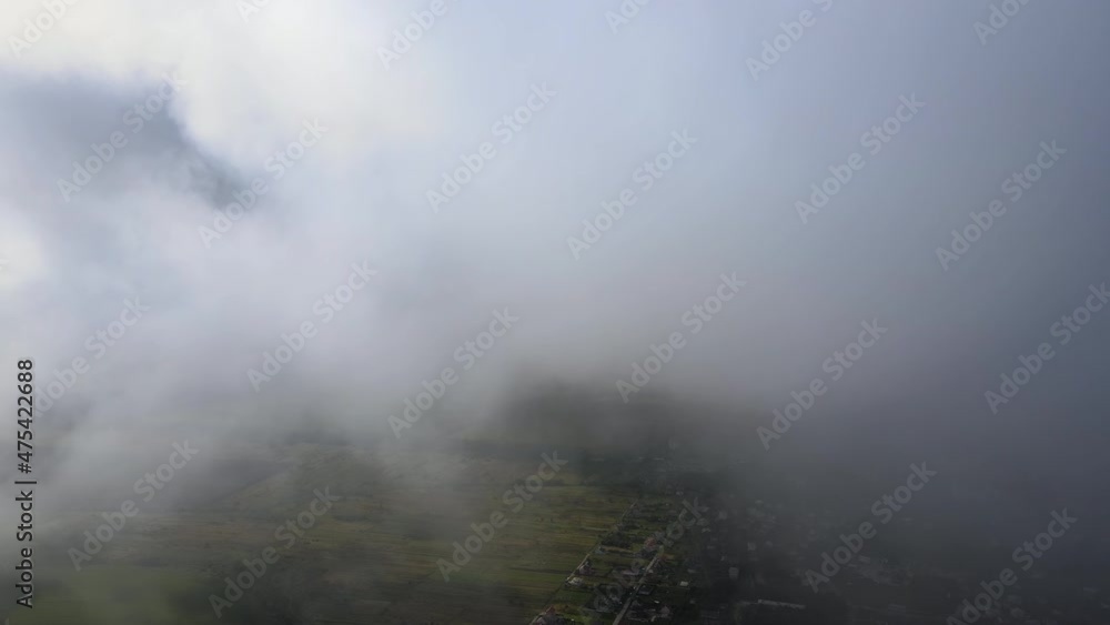 Aerial view from high altitude of distant city covered with puffy cumulus clouds forming before rainstorm Aerial view from high altitude of distant city covered with puffy cumulus clouds forming before rainstorm