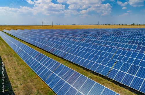 Solar power plant, solar panels shot from a drone, blue sky and clouds