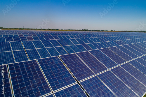 Solar power plant, solar panels shot from a drone, blue sky and clouds